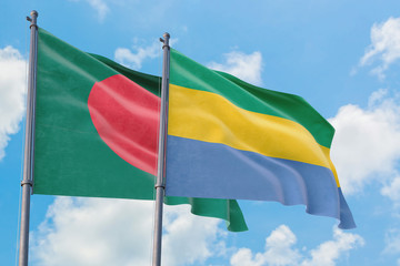 Gabon and Bangladesh flags waving in the wind against white cloudy blue sky together. Diplomacy concept, international relations.