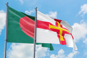 Guernsey and Bangladesh flags waving in the wind against white cloudy blue sky together. Diplomacy concept, international relations.