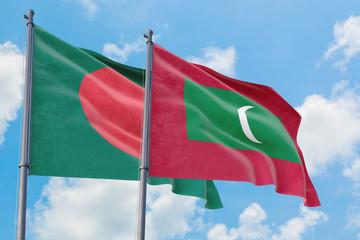 Maldives and Bangladesh flags waving in the wind against white cloudy blue sky together. Diplomacy concept, international relations.