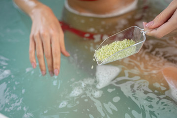 Woman adding salt crystals to the bathwater