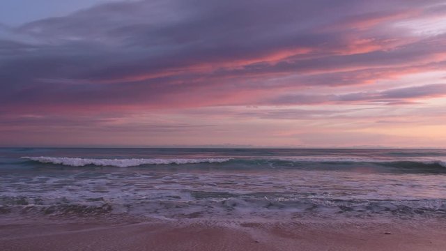 Looking at Atlantic Ocean in Armacao de Pera, Algarve, Portugal. Beautiful colorful sky at sunset. Real time 4K video. Waves crashing at the beach. Ideas are water. Wave of donations. Low light.