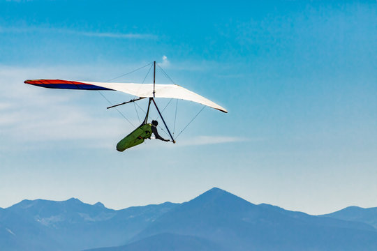Flying hang glider man in action. Beautiful mountains view in the background. Extreme leisure activities in Creston, British Columbia, Canada