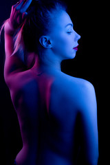 High Fashion model woman in colorful bright lights posing in studio, portrait of a beautiful girl. Artistic colorful design. Party concept, stands with his back