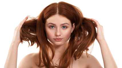 Power of hair. Portrait of a young gorgeous redhead woman playing with her long and healthy ginger hair while standing against white background. Natural beauty