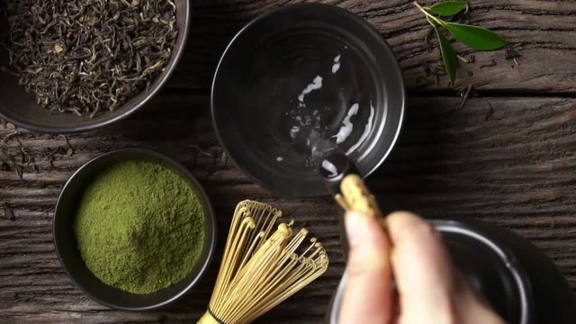 Preparing Japanese organic matcha green tea powder in the black bowl with wire whisk on wooden table, Organic product from the nature for healthy with traditional style