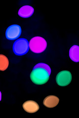 Portrait view of colorful bokeh lights at night appearing against a black backdrop