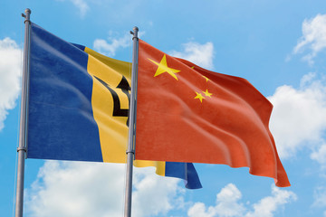 China and Barbados flags waving in the wind against white cloudy blue sky together. Diplomacy concept, international relations.