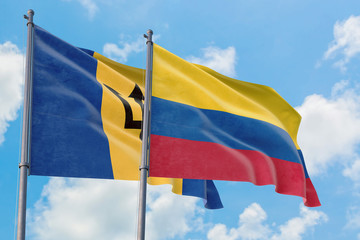 Colombia and Barbados flags waving in the wind against white cloudy blue sky together. Diplomacy concept, international relations.