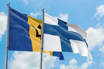 Finland and Barbados flags waving in the wind against white cloudy blue sky together. Diplomacy...