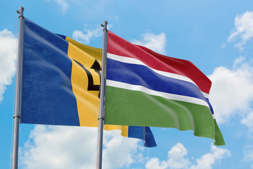 Gambia and Barbados flags waving in the wind against white cloudy blue sky together. Diplomacy concept, international relations.