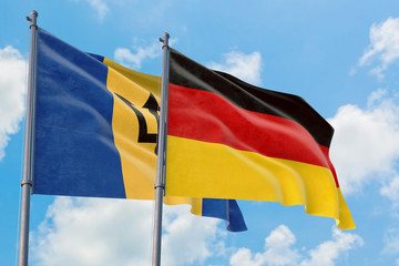 Germany and Barbados flags waving in the wind against white cloudy blue sky together. Diplomacy concept, international relations.