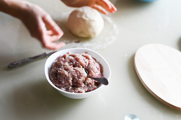 Dough with minced meat. Hands wrinkle the dough closeup. Manual preparation of the test. Homemade baking. Cooking dumplings and pasties.