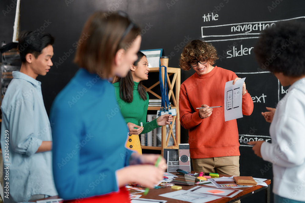 Canvas Prints user interface design. young and positive professional designer is showing some sketches to his coll