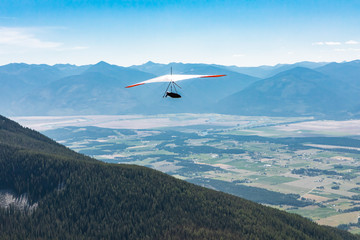 Back view of person Hang-gliding. Professional air sportsman enjoying his recreational journey to Creston, British Columbia, Canada