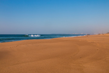 Stretch of Clear Beach Sand with Fishrmen and Buildings in Background