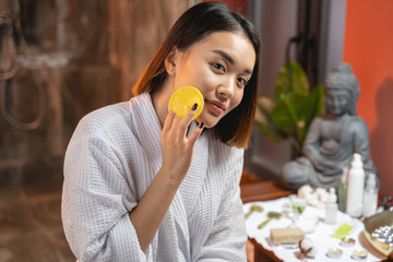 Beautiful Asian lady cleaning her face with sponge