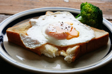 食べかけの半熟目玉焼きを乗せたパンとブロッコリー