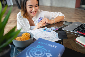 Asian pretty girl analysing her horoscope indoors