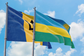 Rwanda and Barbados flags waving in the wind against white cloudy blue sky together. Diplomacy concept, international relations.