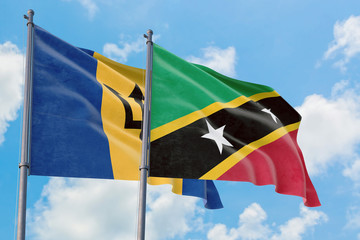 Saint Kitts And Nevis and Barbados flags waving in the wind against white cloudy blue sky together. Diplomacy concept, international relations.