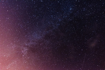 A magical starry night on the river bank with a large tree and a milky way in the sky and falling stars