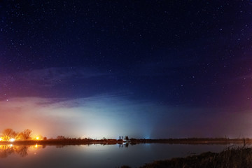 A magical starry night on the river bank with a large tree and a milky way in the sky and falling stars