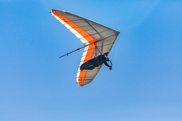 Hang glider flying against a clear blue sky on a sunny day. View from the bottom or overhead....