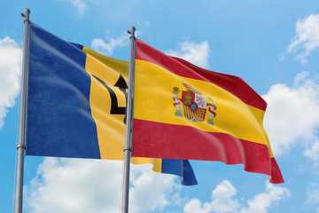 Spain and Barbados flags waving in the wind against white cloudy blue sky together. Diplomacy concept, international relations.