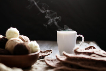 Cup of tea, coffee on an old wooden table against the background of knitting tools.