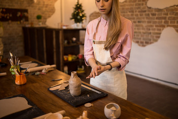 Beautiful girl sculpts a jug of clay in a pottery.
