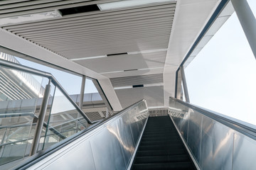 Outdoor elevators and city buildings, with sunlight in front.