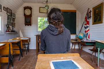 Real school class of the 1920th in Kootenays, British Columbia, Canada. Rear view of man sitting in the vintage class from the past century