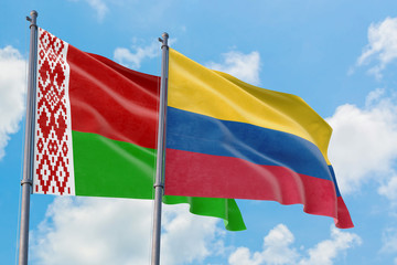 Colombia and Belarus flags waving in the wind against white cloudy blue sky together. Diplomacy concept, international relations.