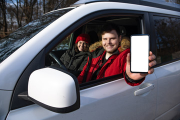 couple sitting in rent car man holding phone with white empty screen