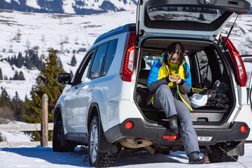 woman sitting in suv car trunk full of ski and snowboard stuff