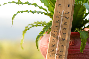 Outdoor wood thermometer calibrated in celsius and fahrenheit scale showing 15 degrees celsius or 60 degrees fahrenheit on terrace with landscape mountains view