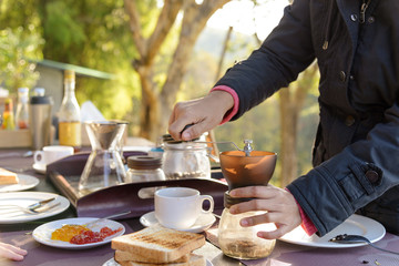 Asian women hands on manual grinder coffee for grinding coffee beans on table with natural green background feeling chill and relax in nature