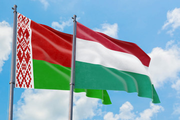 Hungary and Belarus flags waving in the wind against white cloudy blue sky together. Diplomacy concept, international relations.