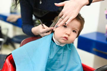 A child at the hairdresser. The first haircut of the child at the hairdresser. Baby haircut toddler.