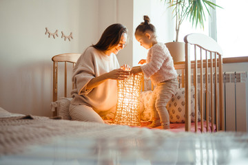 Cheerful mother and her little daughter watching at the lamp. Happy young woman and her little cute daughter enjoy the night light. Happy loving family. 
