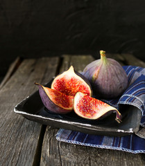 Sliced pieces of ripe figs on an old wooden background.