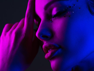 Portrait of the girl is highlighted in bright blue and purple light. Face of a beautiful model....