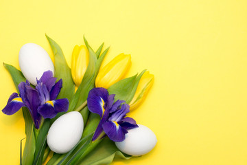 Bright yellow background with spring Easter flowers and eggs with a copy space