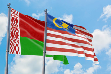 Malaysia and Belarus flags waving in the wind against white cloudy blue sky together. Diplomacy concept, international relations.