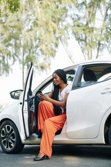 Pretty positive young woman sitting in new car and checking text messages in her phone © DragonImages