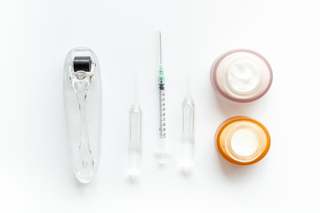 Dermatologist work desk with tools. Dermaroller, syringe, ampoule on white background top-down flat...