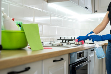 Fototapeta na wymiar young woman cleaning in rubber gloves and sponge in the kitchen at home