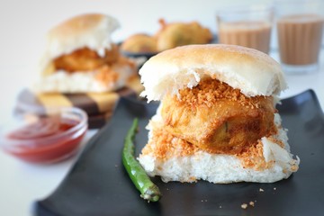Vada pav or wada pao is a vegetarian fast food dish native to the state of Maharashtra. Famous Mumbai street food served with Red chutney and fried green chili. Copy space