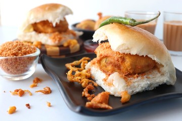 Vada pav or wada pao is a vegetarian fast food dish native to the state of Maharashtra. Famous Mumbai street food served with Red chutney and fried green chili. Copy space