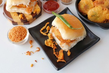 Vada pav or wada pao is a vegetarian fast food dish native to the state of Maharashtra. Famous Mumbai street food served with Red chutney and fried green chili. Copy space